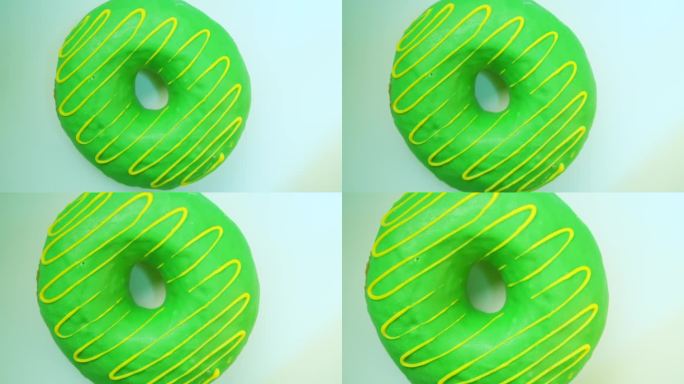 轻盈的甜甜圈，点缀着绿色的糖果釉，香草奶油糖霜和软糖，在浅色的背景下旋转。