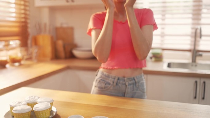 女人在厨房里微笑着展示新鲜的纸杯蛋糕，慢镜头