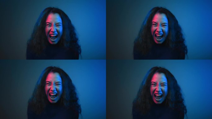 年轻女子的肖像看着相机和霓虹彩色拍摄尖叫。愤怒的生活方式的一个亚洲女士在仇恨艰苦的生活大喊大叫。愤怒