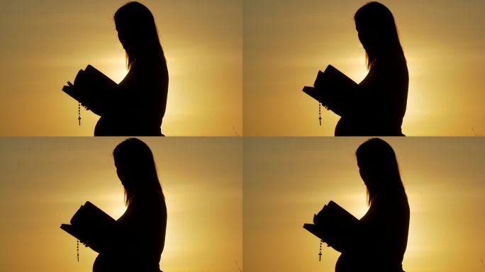 一位孕妇在夕阳下揉着肚子，带着十字架读《圣经》