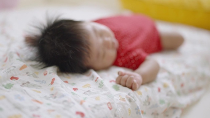 一个月大的男婴在父母卧室舒适的床上睡觉的特写。