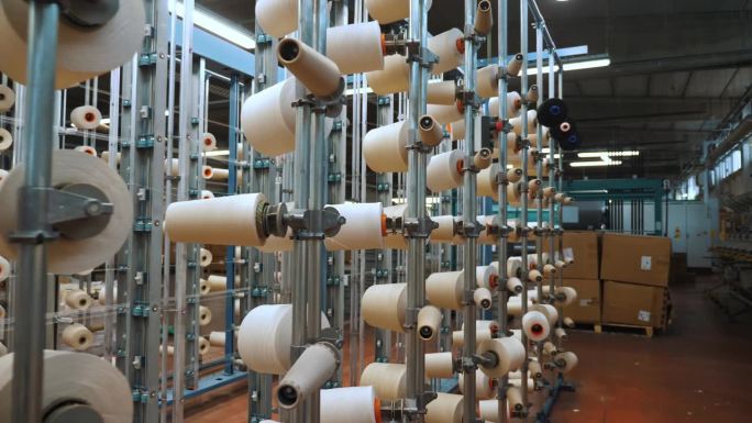 线轴上。纺织工业。纺织工厂。有许多线轴的机架。为进一步生产织物而对纱线进行染色和干燥。自动化的工作流
