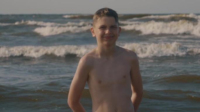 男孩在海滩上微笑。海的背后