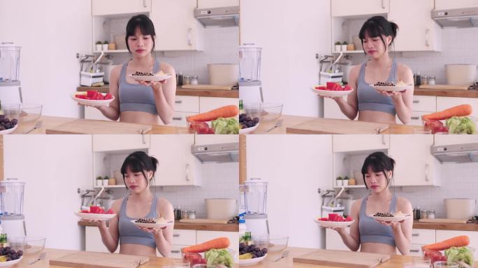 一个爱运动的亚洲女人陷入了两难的境地，在她的厨房里，她决定是沉迷于一盘诱人的甜点，还是选择更健康的水
