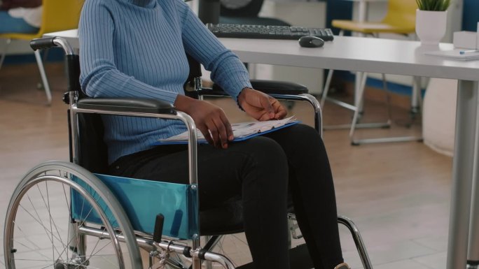 瘫痪的残疾人坐在轮椅上，拿着剪贴板