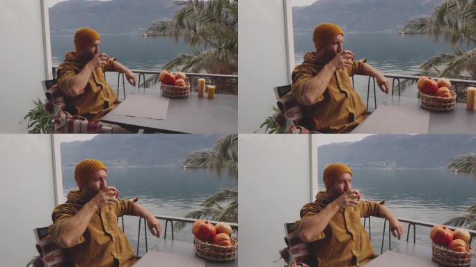 一名男子在自家湖边的阳台上喝着茶休息