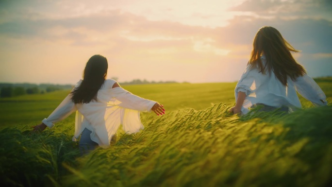 夕阳下，兴奋的女人在绿色的麦田里奔跑