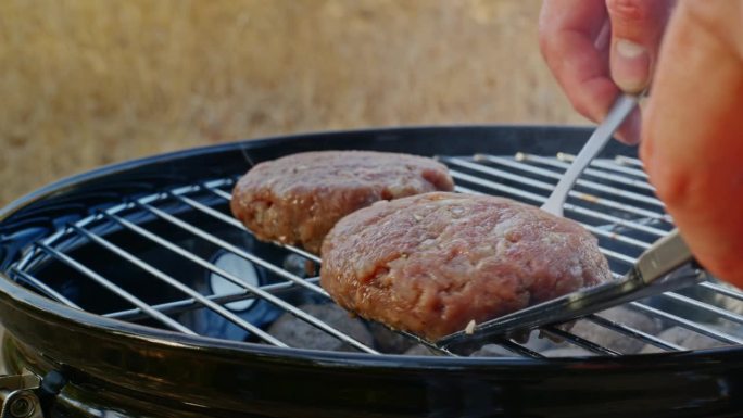 两块烤肉排被烤好，用叉子和抹刀翻过来。