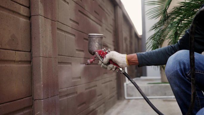 工人用喷枪粉刷房屋外墙的特写。