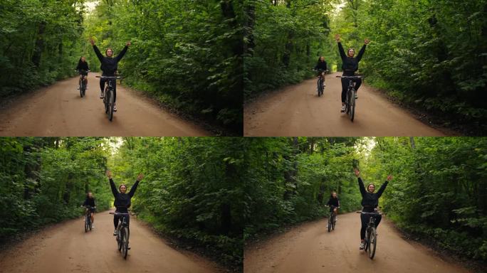 一群年轻的女性朋友在夏天骑自行车在森林里，有趣的女孩骑自行车没有手