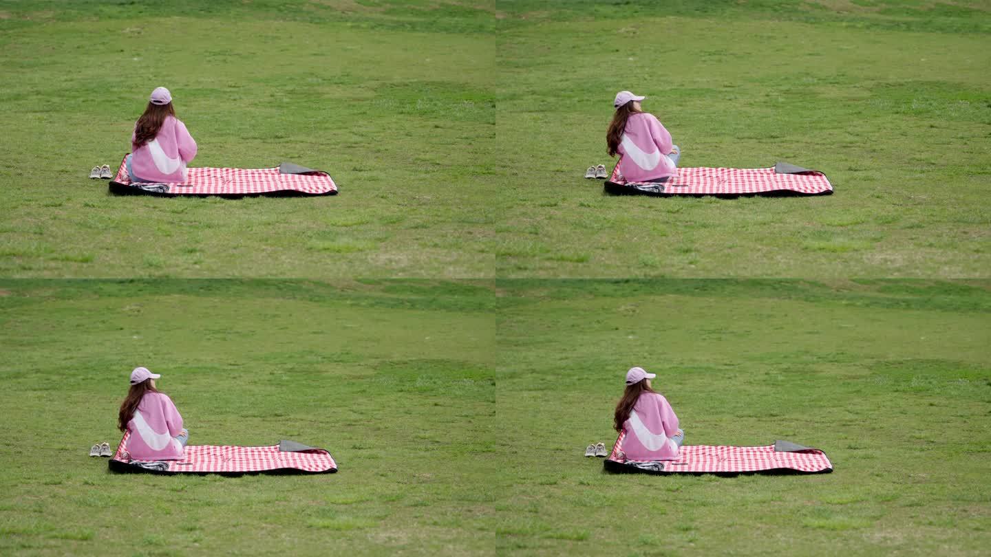 公园草坪坐着的女生背影