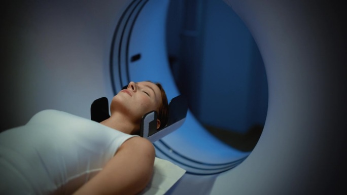 一位躺在CT或MRI扫描上的女性病人的特写肖像，当机器扫描她的身体和大脑时，床在机器内部移动。拥有高