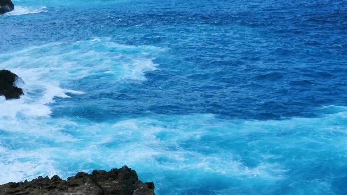 蓝绿色的海洋海水白色的波浪溅深蓝色的大海。鸟瞰怪物波浪飞溅在岩石上。热带海滩在夏季海边户外。大洋岛风