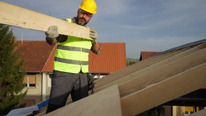 白人男性屋顶工人，在建筑工地的屋顶梁上工作