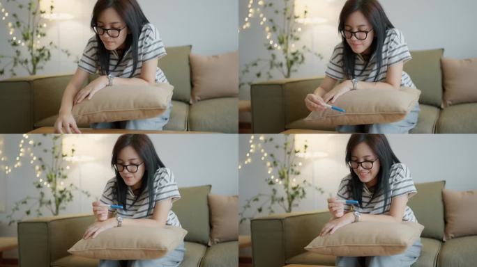 快乐的亚洲年轻女子在家阅读验孕结果。