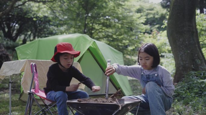 日本的兄弟和姐妹把树枝放在一起作为露营的火坑