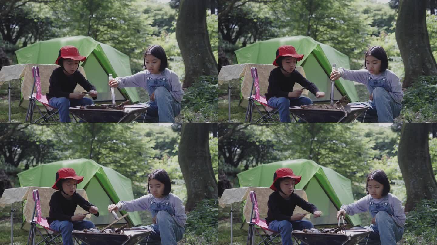 日本的兄弟和姐妹把树枝放在一起作为露营的火坑