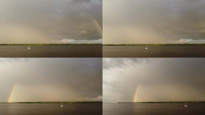 风暴过后的一个湖的视频，有帆船，乌云，从右到左的平移显示了彩虹的两边