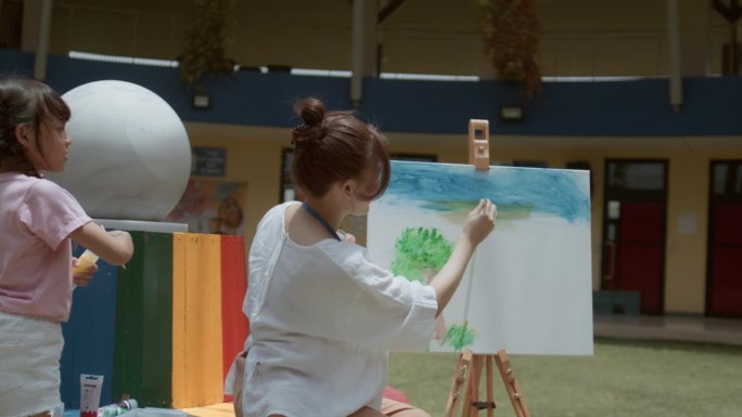快乐的老师用水彩画和孩子们一起在学校操场上玩耍。