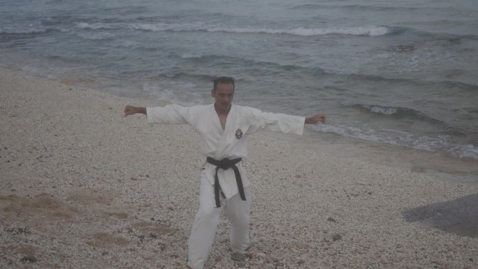 一名男子在沙滩上慢镜头练习空手道技巧