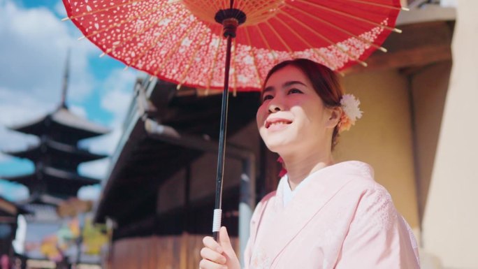 老妇人穿着和服，撑着红伞，在日本老城村庄享受旅行