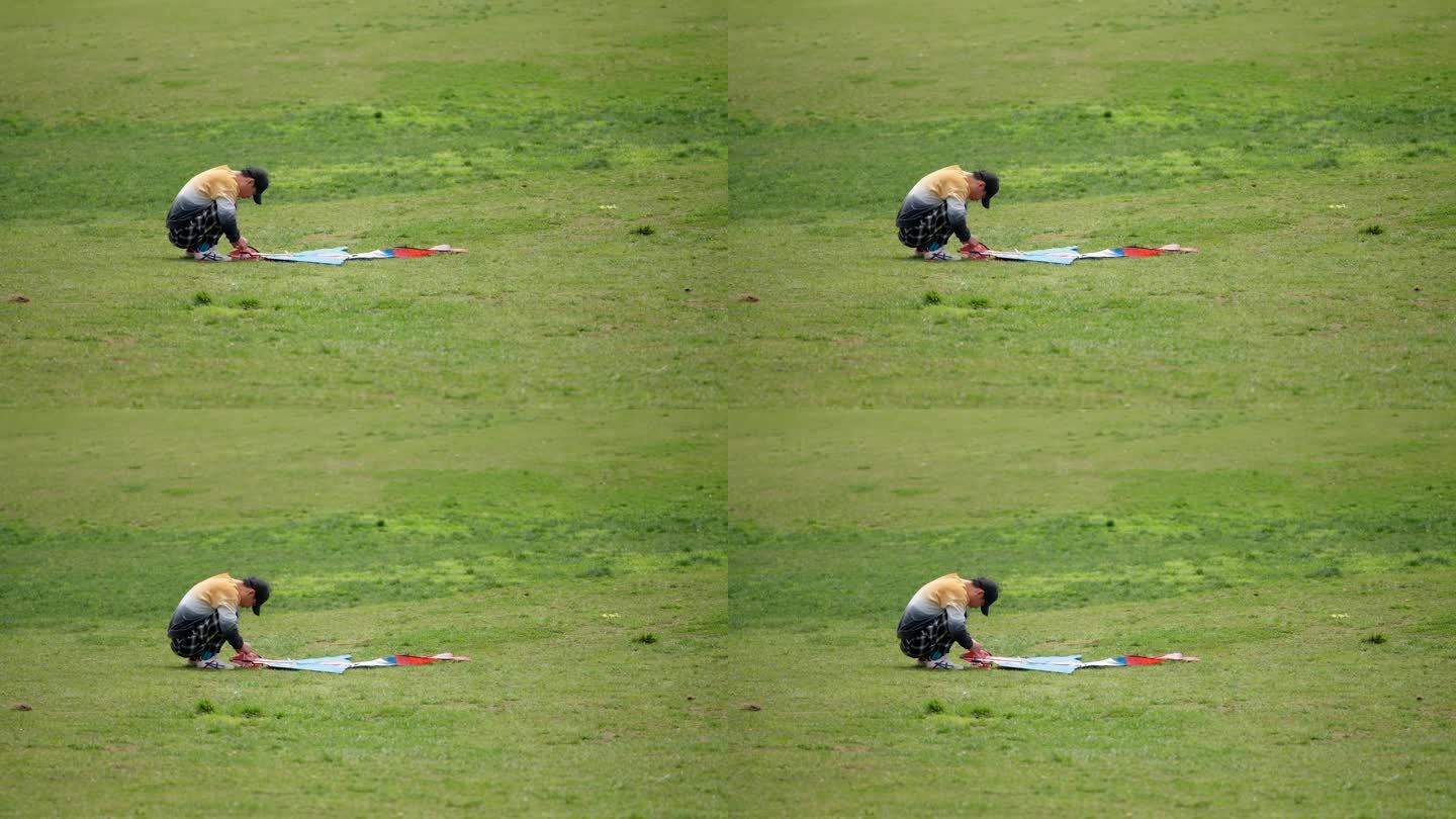 公园草坪上修理风筝的男生