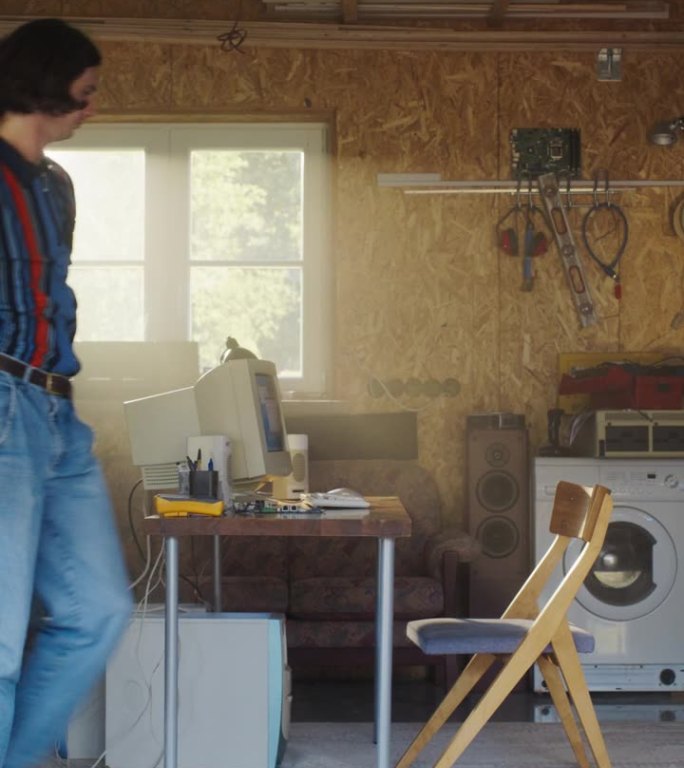 竖屏:白人男子打开车库门，坐在复古车库的旧台式电脑后面。90年代男性电子商务创业创始人开创在线服务。