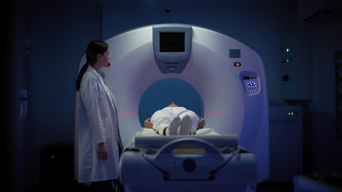 在医学实验室，躺在CT或MRI扫描床上的女性患者在专业放射科医生的监督下接受扫描程序。影像在医学实验