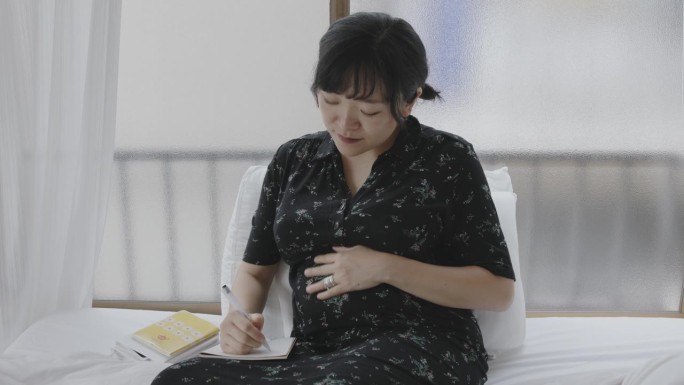 年轻的日本妇女正在写她的怀孕日记