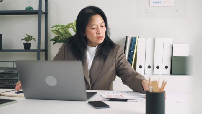 亚洲女商人在现代办公室用笔记本电脑做营销计划