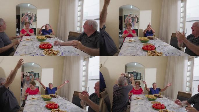 兴高采烈的老朋友们坐在餐桌旁庆祝上菜。老人在午餐聚会。老妇人带饭来