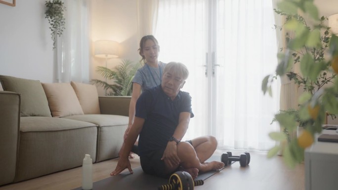 活跃的健康老人在客厅地板上的瑜伽垫上锻炼。