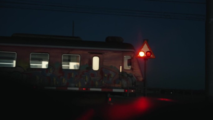 火车穿过铁路道口，护栏升起，晚上从汽车上看