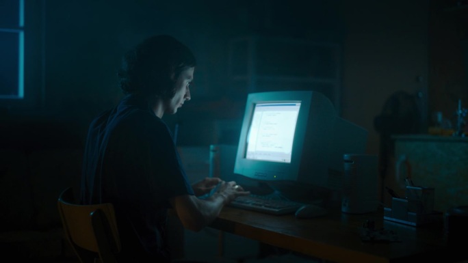 白人男性网页设计师深夜在复古车库使用旧台式电脑。专注的互联网爱好者在家写代码。九十年代成功的在线论坛