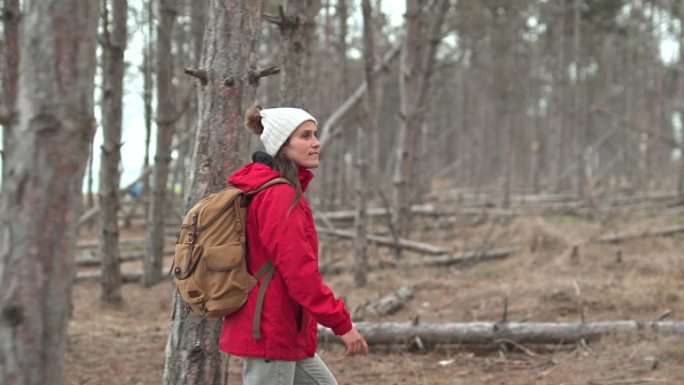 穿红衣服的女人在树林里徒步旅行。回归自然。