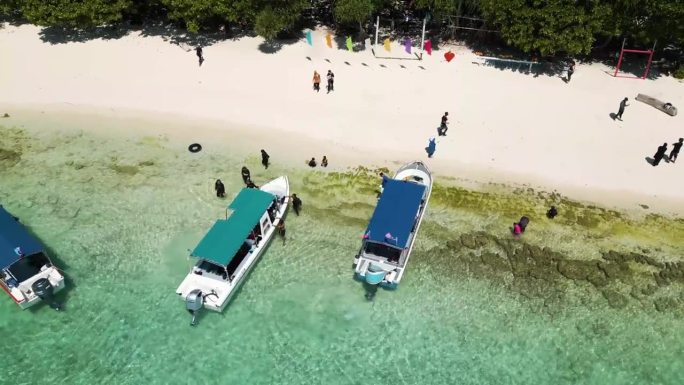 航拍的海滩与停靠的旅游船，地点跳岛在沙巴，马来西亚，目的地展开了一个独特的章节自然美景和文化的丰富。