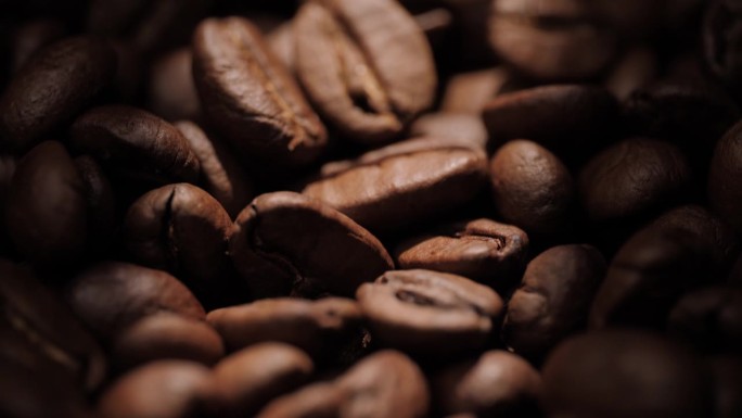 咖啡豆。镜头慢慢向下移动，在阳光照耀下，在阴影中显示出令人敬畏的烘焙咖啡豆。微距镜头