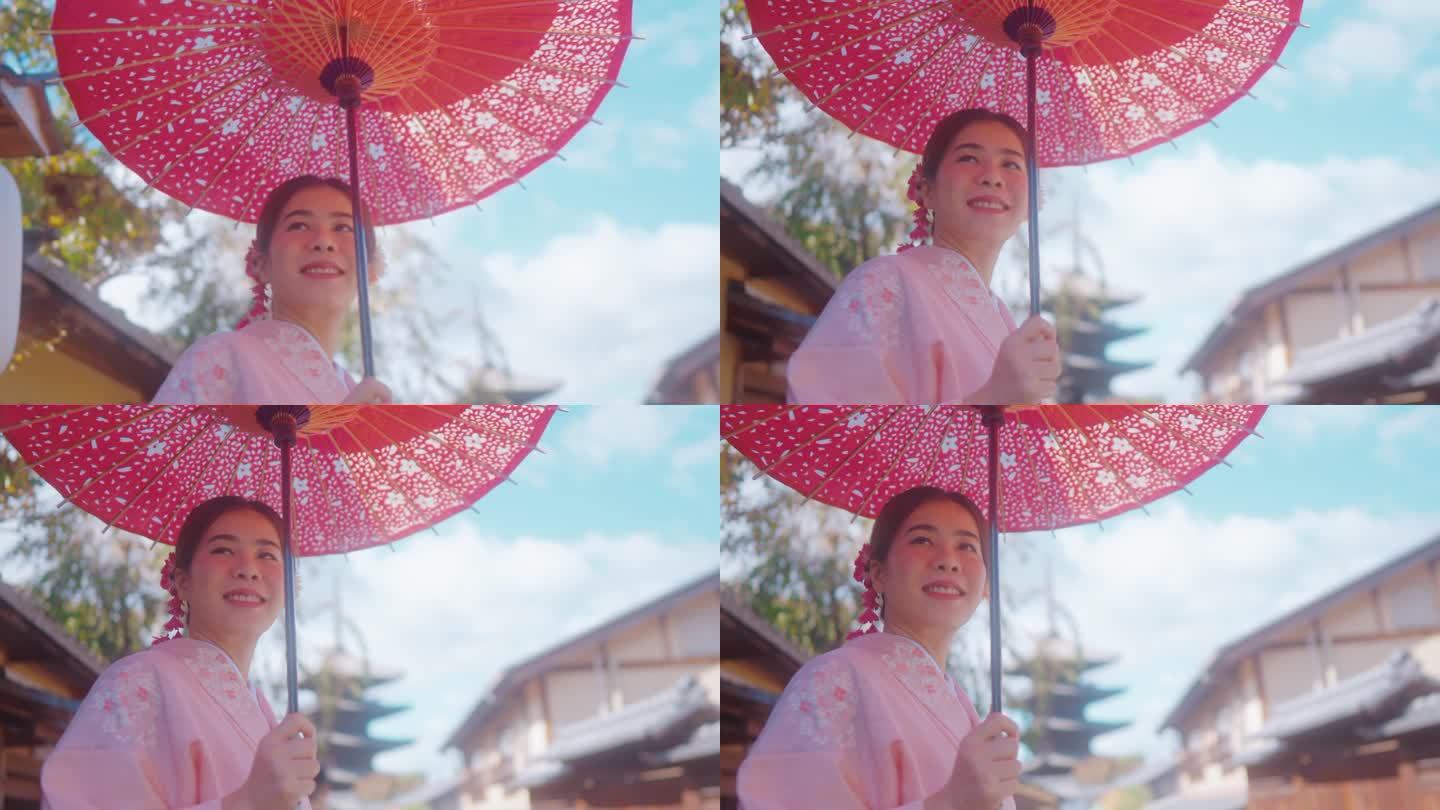 老妇人穿着和服，撑着红伞，在日本老城村庄享受旅行