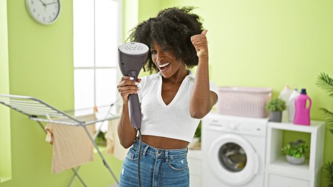 非裔美国妇女在洗衣房拿着立式熨烫机竖起大拇指