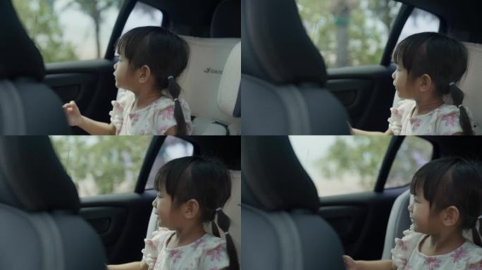 可爱的小女孩坐在汽车后座上，看着窗外，和家人一起去海滩