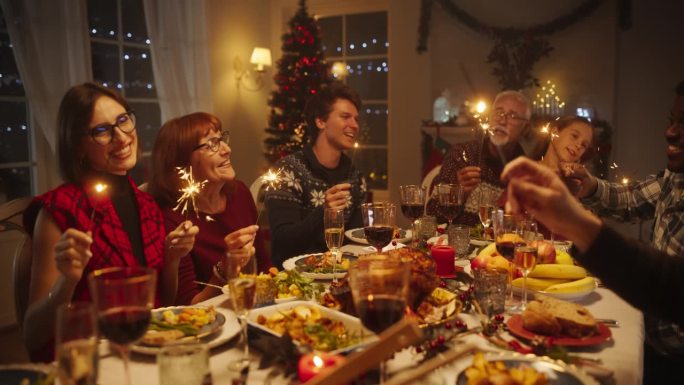 家人和朋友聚在家里吃传统的圣诞晚餐，烤火鸡盛宴。快乐的成功人士庆祝节日，一起唱圣诞颂歌，拿着烟花