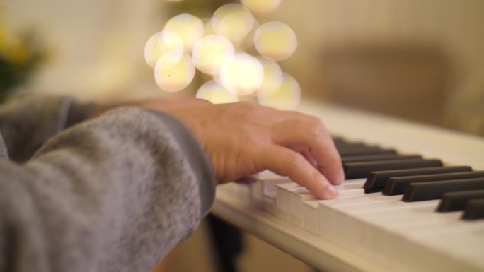 圣诞节，亚洲父亲在客厅与家人弹钢琴的特写。