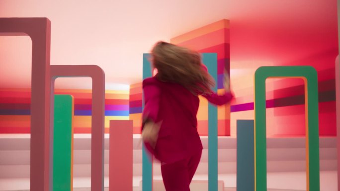 放大:在工作室环境中，专业舞者在彩色背景的大数字Led墙屏幕前表演舞蹈的肖像。她正在与装饰道具互动