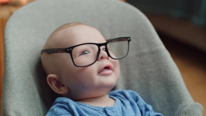 戴眼镜的婴儿。聪明的屁股。剪短的手的母亲给婴儿戴上眼镜的男孩放松在家里的保镖。有趣的场景