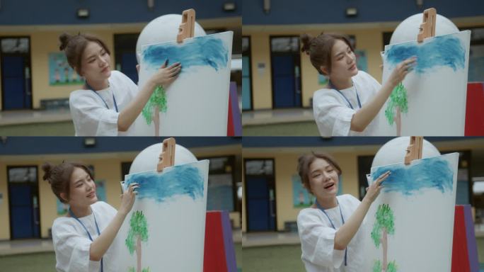 亚洲年轻成年女教师在学校操场的美术课上给多种族小学生讲授丙烯画。