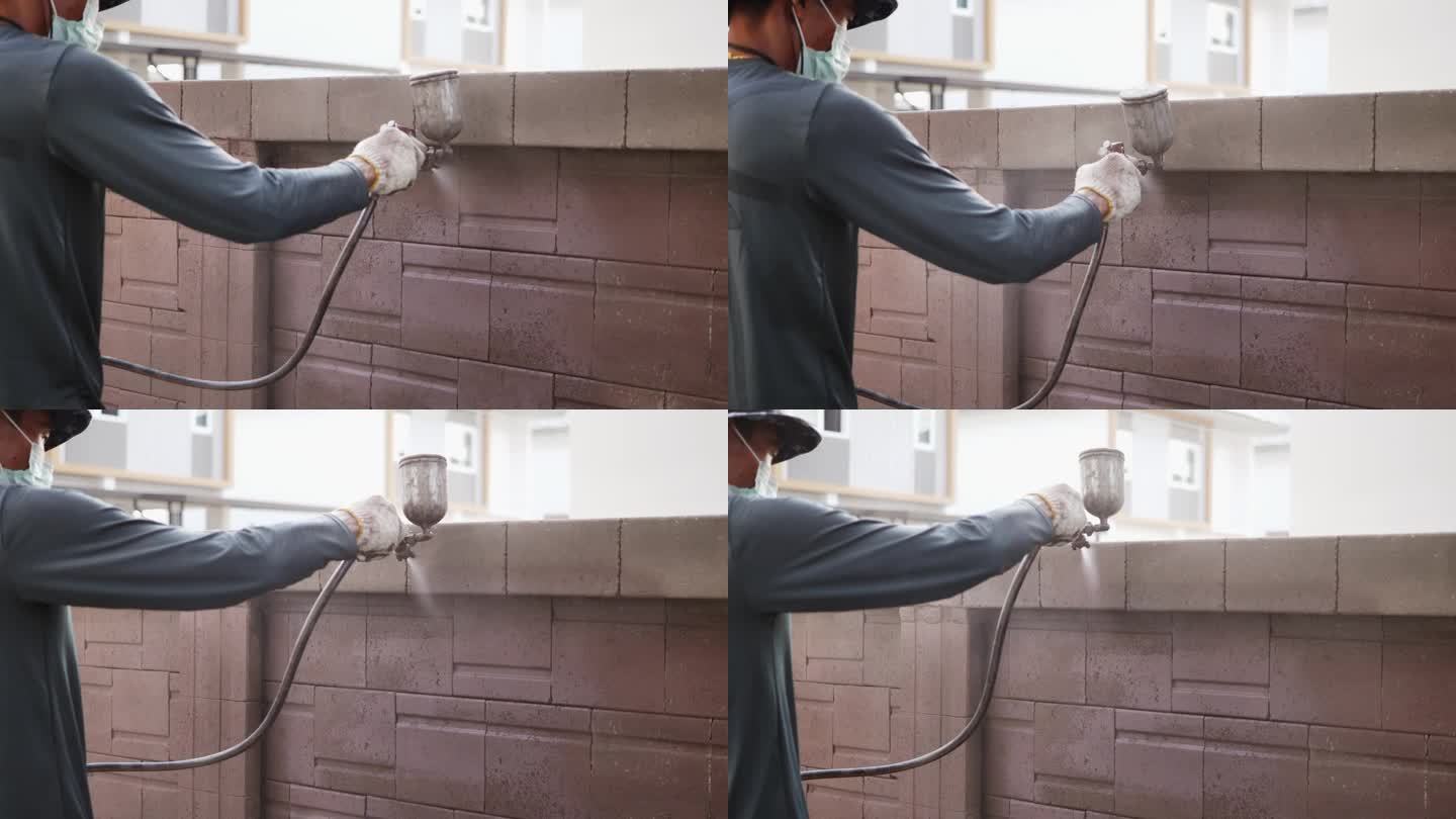 亚洲建筑工人用喷枪粉刷墙壁。