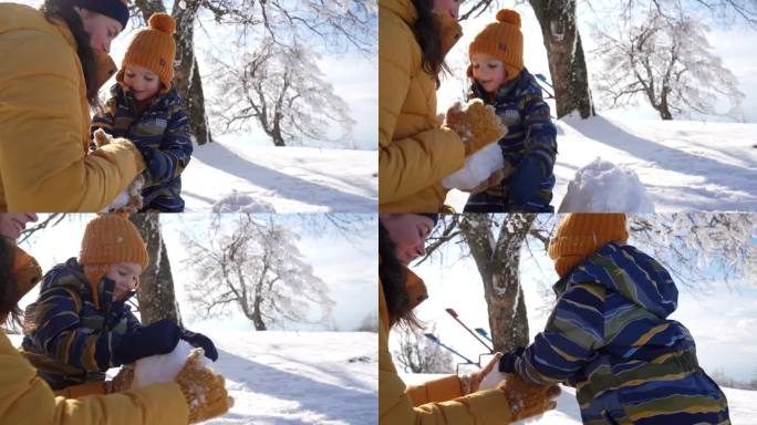 蹒跚学步的小男孩帮妈妈堆雪人