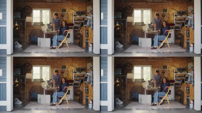 两个白人男性创业公司创始人在复古的车库里使用旧台式电脑，看着相机微笑。程序员和用户体验设计师在90年