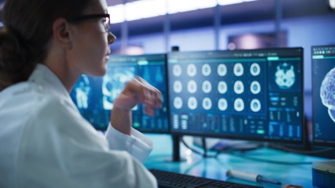 医院研究实验室:女医学家用计算机与脑扫描MRI图像。专业神经学家分析CT扫描，为脑损伤患者寻找治疗方