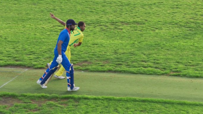 一名穿着黄绿制服的南亚板球运动员在球场上投球的肖像。职业印度投球手的目标是击中三柱门。体育电视频道广